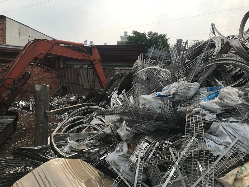 Xe cuốc bốc xếp đống phế liệu kim loại tại bãi tập kết